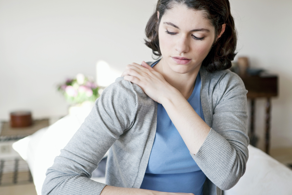 woman holding her shoulder because she is in pain